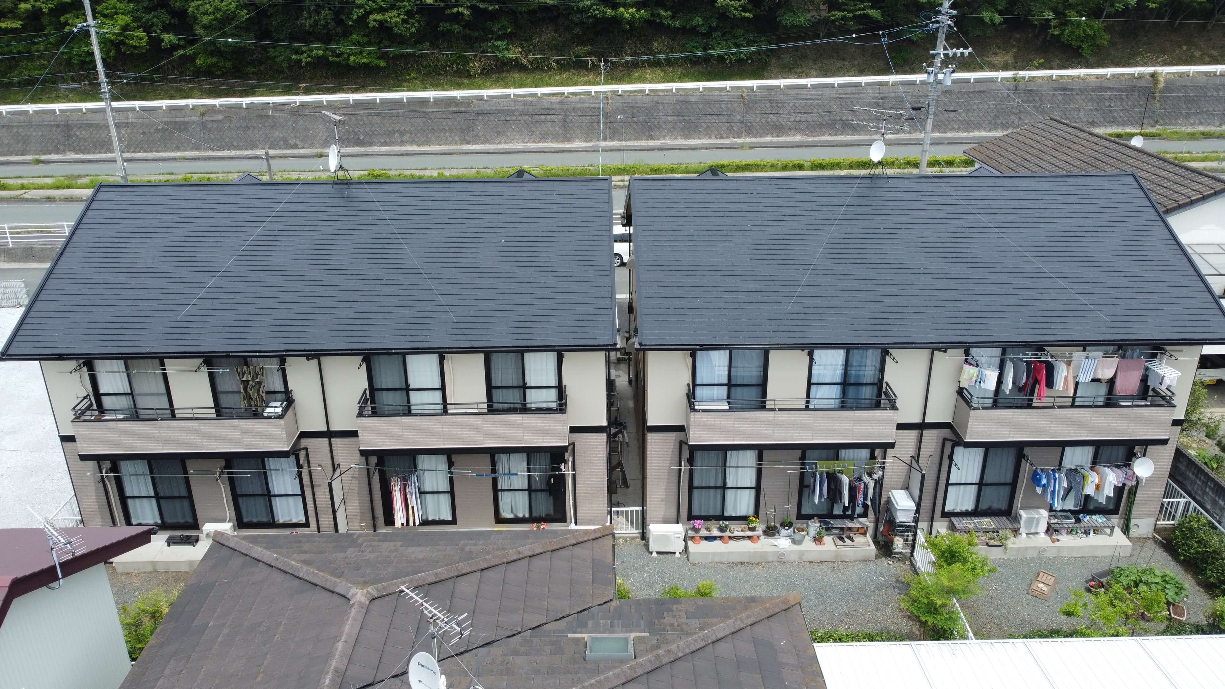 黒い屋根を持つ二棟の住宅が並んでおり、両側にバルコニーがある2階建ての建物